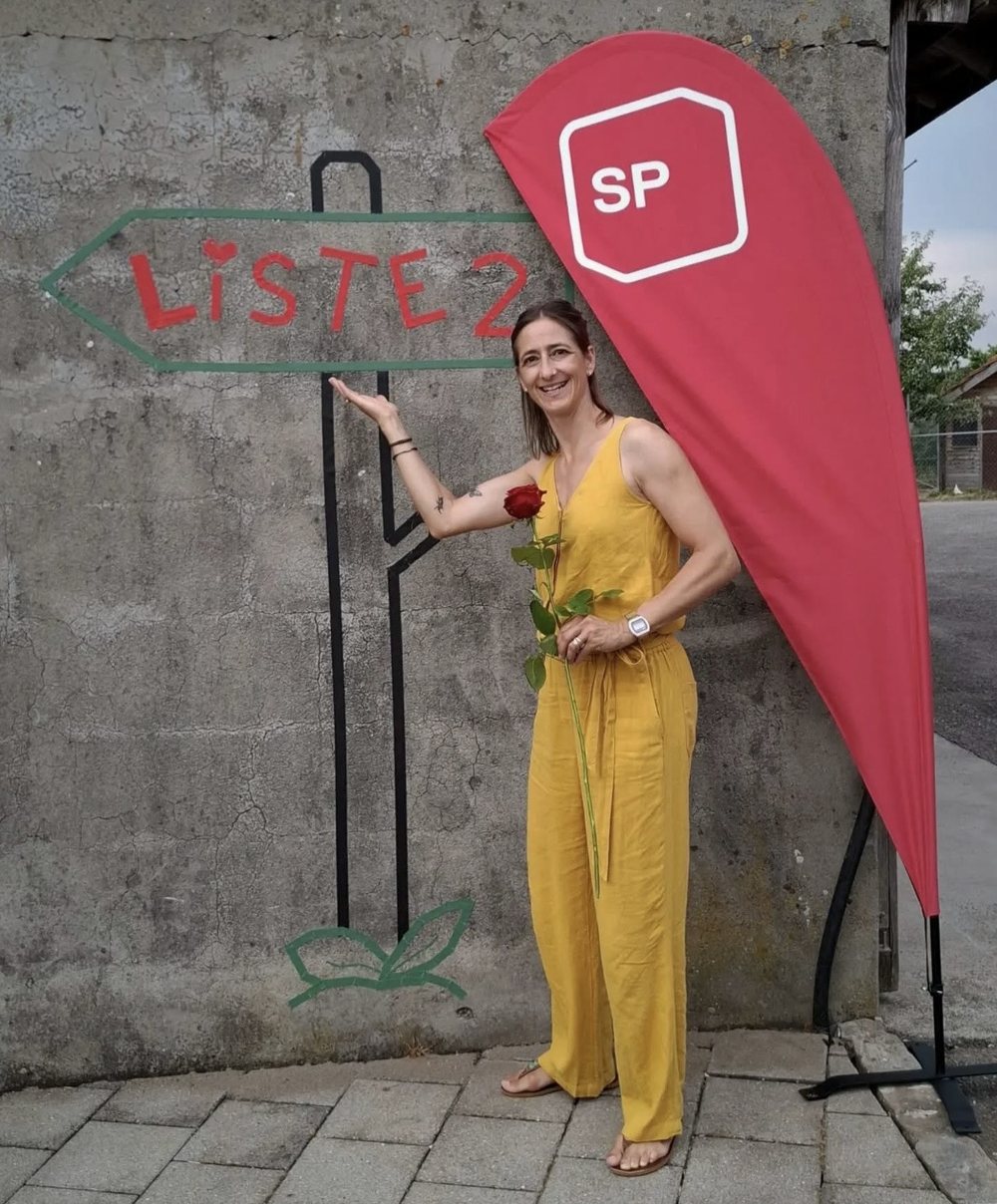 Stephanie Tschopp in gelbem Overall mit SP-Fahne
